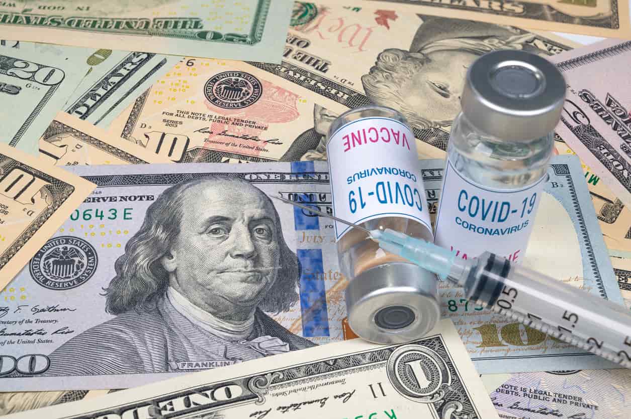 COVID-19 vaccine atop a pile of money