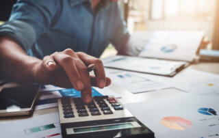 Business man using calculator with computer laptop, budget and loan paper in office